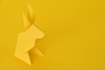 Yellow origami paper rabbit on yellow background.