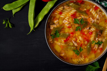 Minestrone, italian vegetable soup with pasta on black table. Top view, flat lay, copy space