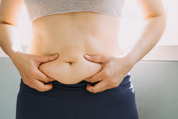 Beautiful fat woman with tape measure She uses her hand to squeeze the excess fat that is isolated on a white background. She wants to lose weight, the concept of surgery and break down fat under the