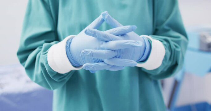 Video of midsection of surgeon wearing surgical gloves and gown in operating theatre