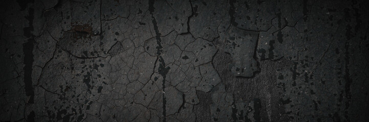 Obraz premium Dark wide panoramic background. Peeling paint on a concrete wall. Dark grunge texture of old cracked flaking paint. Weathered rough painted surface. Patterns of cracks. Darkness background for design.
