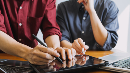 Asian colleagues man and woman discussing and working with laptop computer on office desk in the office