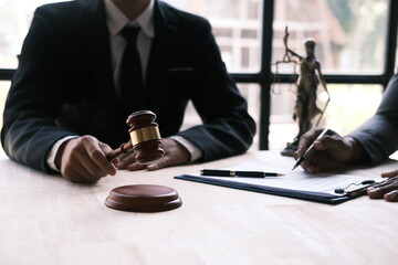 Judge gavel with Justice lawyers having team meeting at law firm in background. Notary with client in office. lawyer concept.