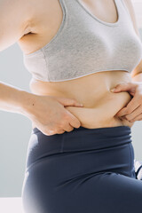 Beautiful fat woman with tape measure She uses her hand to squeeze the excess fat that is isolated on a white background. She wants to lose weight, the concept of surgery and break down fat under the