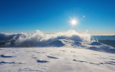 Sun and clouds over the mountains covered with snow. The mountain slope covered with ice and snow...