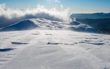 Clouds over the mountain peak. The mountain slope covered with ice and snow during snowstorm.