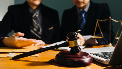 Business and lawyers discussing contract papers with brass scale on desk in office. Law, legal services, advice, justice and law concept picture with film grain effect