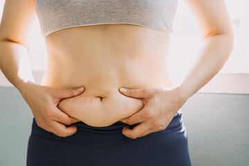 Beautiful fat woman with tape measure She uses her hand to squeeze the excess fat that is isolated on a white background. She wants to lose weight, the concept of surgery and break down fat under the