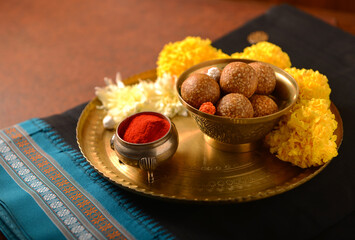 Traditional Indian black color Saari and Til Laddoo in puja thali. Makar Sankranti festival objects...