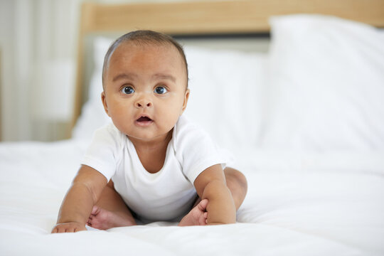 African newborn baby sitting on bed at home