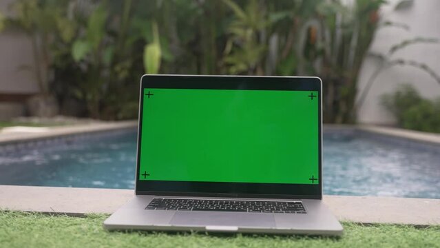 Laptop computer lying on the banks of the pool, slow motion shot 