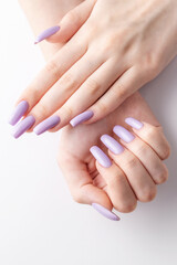 Hands of a girl with a soft purple manicure on a white background.