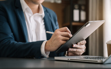 Fototapeta premium Send a message to a colleague, a businessman, confident in matching a tablet and sitting in office.