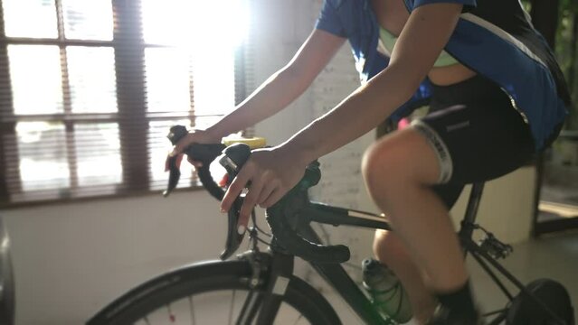 Asian woman cyclist. She is exercising in the house.By cycling on the trainer and play online bike games	
