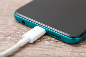White cable connected to the phone. Charging modern smartphone with USB type c cable