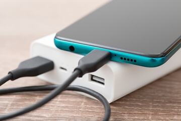 Close up shot of mobile phone charging from power bank. Using modern USB type c cable for charging...