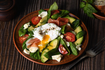 Eggs Benedict (Poached) with Parma ham, slices of avocado, tomato and tender spinach leaves, seasoned with flavored spicy olive oil