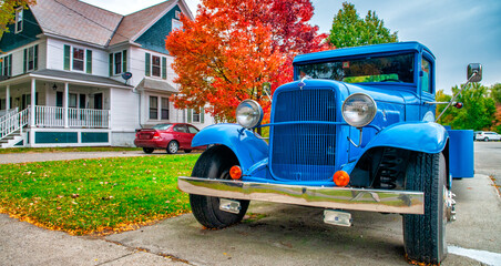 Old vintage blue car in a foliage landscape with house and trees