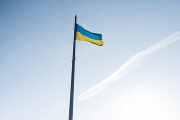 Large national flag of Ukraine flies in the blue sky. Big yellow blue Ukrainian state banner.