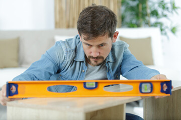 carpenter at work with spirit level on wood background