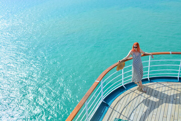 Woman with orange hair lounging on front of boat with beautiful blue ocean behind her