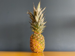 Pineapple on yellow sideboard against petrol blue wall.