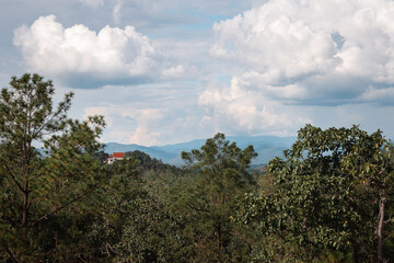 Obraz premium View over tropical forest with a monastery and mountains in the distance