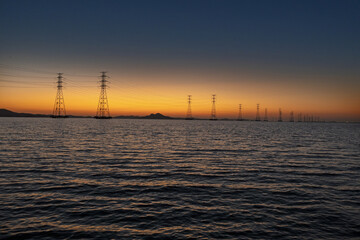 바다에 설치된 송전탑과 그 뒤로 보이는 석양