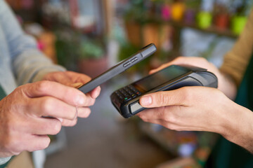 Hände halten Smartphone und NFC Kartenterminal