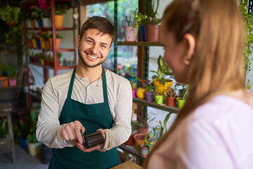 Florist mit NFC Lesegerät und Kundin beim Bezahlen