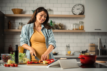 Beautiful pregnant woman preparing delicious food. Smiling woman preparing delicious food.