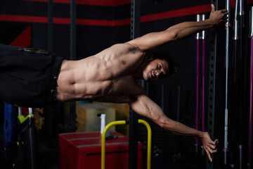Fototapeta na wymiar young athletic man exercising and pulling up on vertical bar in the gym