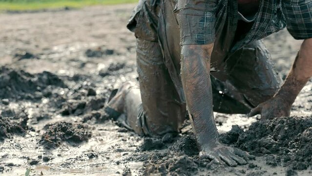 A drunken unfortunate man crawls through the swamp in dirty clothes. A homeless alcoholic drunkard who fell into the swamp.