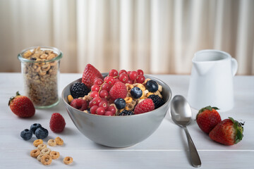 Cereal bowl with berries and milk on a white table. Healthy eating concept. Front view