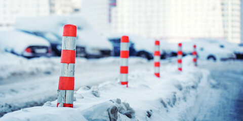 Plastic road cones mounted on snowy winter urban street