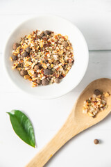 various spices on a wooden spoon on white wooden background with other white kitchenware and green leaves. High quality photo