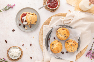 Homemade raisin scones with clotted cream and strawberry jam ready to eat