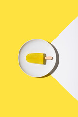 Paleta de hielo sabor limón. Palo de helado sobre fondo amarillo y blanco. Concepto de verano. Vista superior