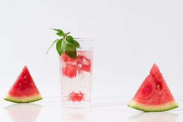 Vaso de zumo de sandía con trozos de sandia y hielo sobre fondo claro	