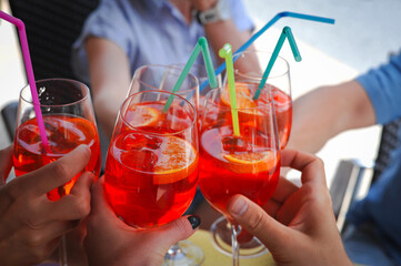 group of friends toast with pink cocktails aperol spritz