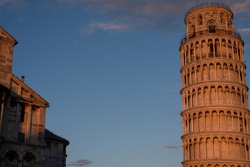 Low angle view of the Pisa tower against sunset blue cloudy sky.