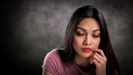 Close-up of a young woman with a thoughtful facial expression - studio photography