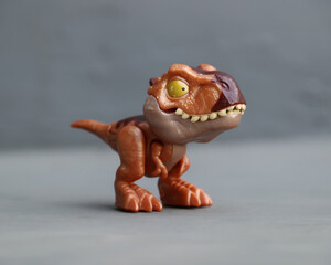 small Tyrannosaurus Rex dinosaur toy with brown color and gray background