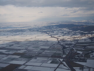 空撮した、雪で覆われた北海道のの田んぼと住宅地