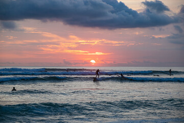 Sunset at Batu Bolong beach, many surfers in ocean on background. Bali, Indonesia