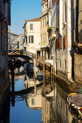 Fototapeta premium Boats covered from rain parked in the water next to the house in canal of Venice. Water transport and transportation theme. Morning in Venice.