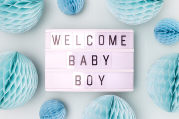 Welcome baby boy. Lightbox with letters and tissue paper balls in a blue color. Festive concept.