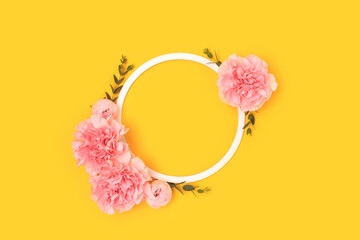 Wreath made of pink rose, carnation flowers and green eucalyptus branches on a yellow background. Cute festive concept.