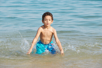 Happy child playing in the sea. Kid having fun outdoors. Summer vacation and healthy lifestyle concept. 