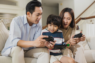 happy Asian family, dad playing game with son and mom at home